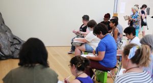People sitting sketching in a Museum setting