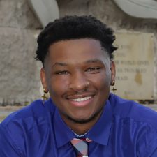 Antojuan Spoons: a young African American. male wearing a royal blue dress shirt and plaid tie