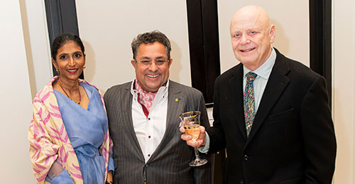 docent-trio three adults dressed in party clothes at a reception with one holding a glass of white wine